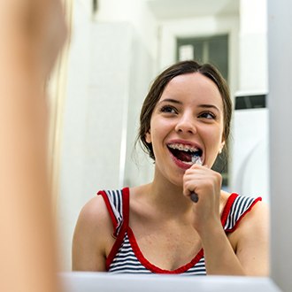 a patient with braces brushing their teeth