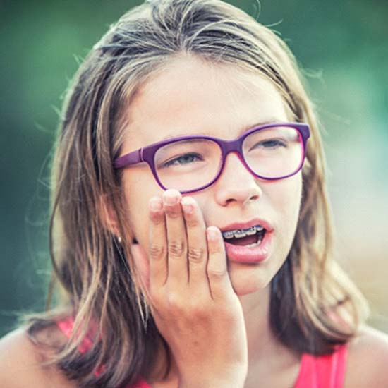 Young girl experiencing an orthodontic emergency in Milford