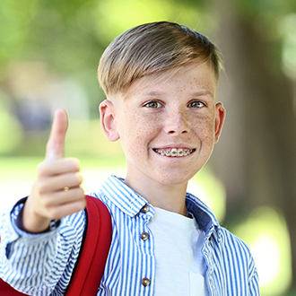 Preteen boy with braces smiling and giving thumbs up