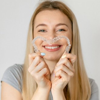 Smiling patient creating heart with aligners