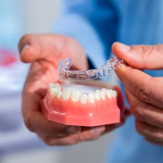 Milford orthodontist putting Invisalign on model of teeth