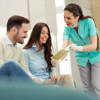 Assistant explaining cost of Invisalign in Milford to couple