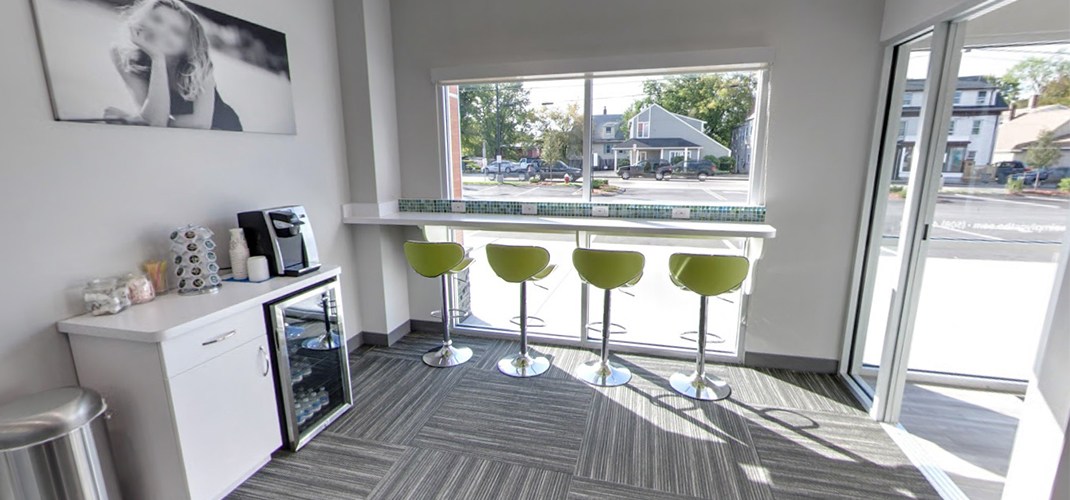 Complimentary beverages and chairs looking out at Milford view in dental office waiting area