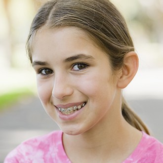 Preteen girl smiling with pediatric orthodontics visible