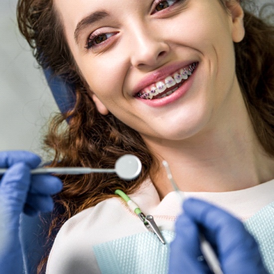 A young female sees an orthodontist in Milford while smiling and showing off her metal braces