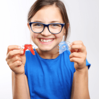 Young girl holding up orthodontic appliances