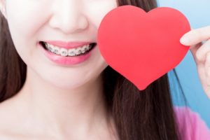 Smiling girl with braces in Milford holding a paper heart valentine