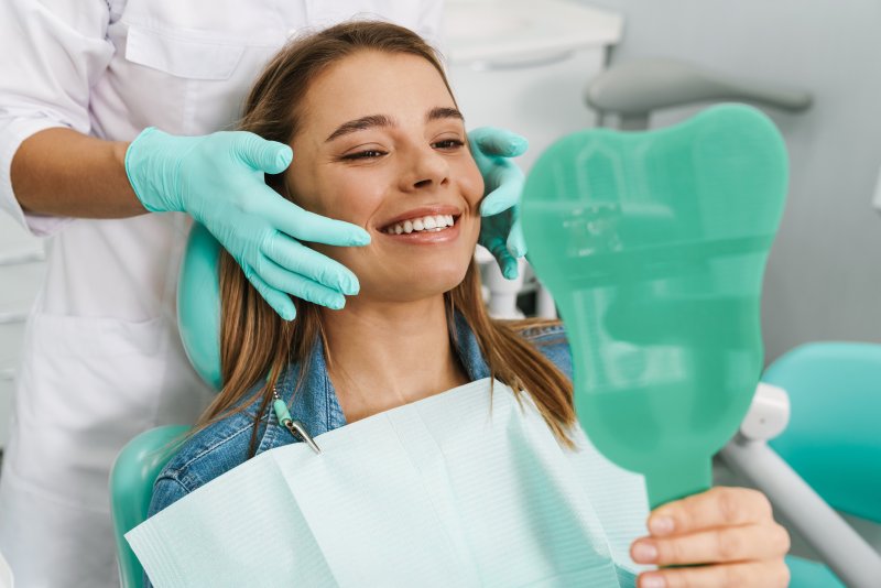 Young woman smiling while looking at teeth in mirror