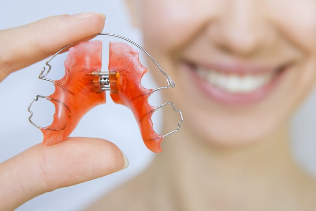 Closeup of dental retainer being held by smiling woman