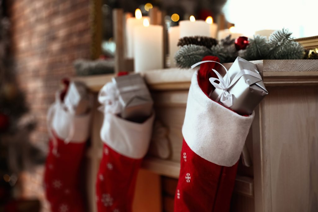 Silver presents placed inside red stockings on fireplace