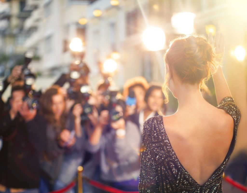 Celebrity waving to paparazzi on red carpet