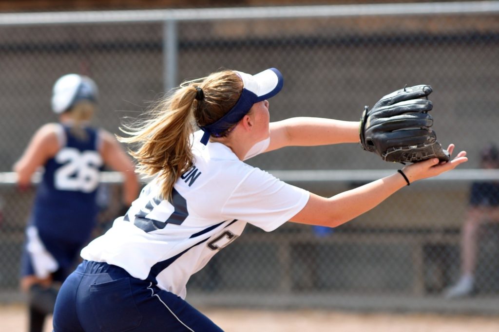 Teen girl using glove and hand to catch softball 