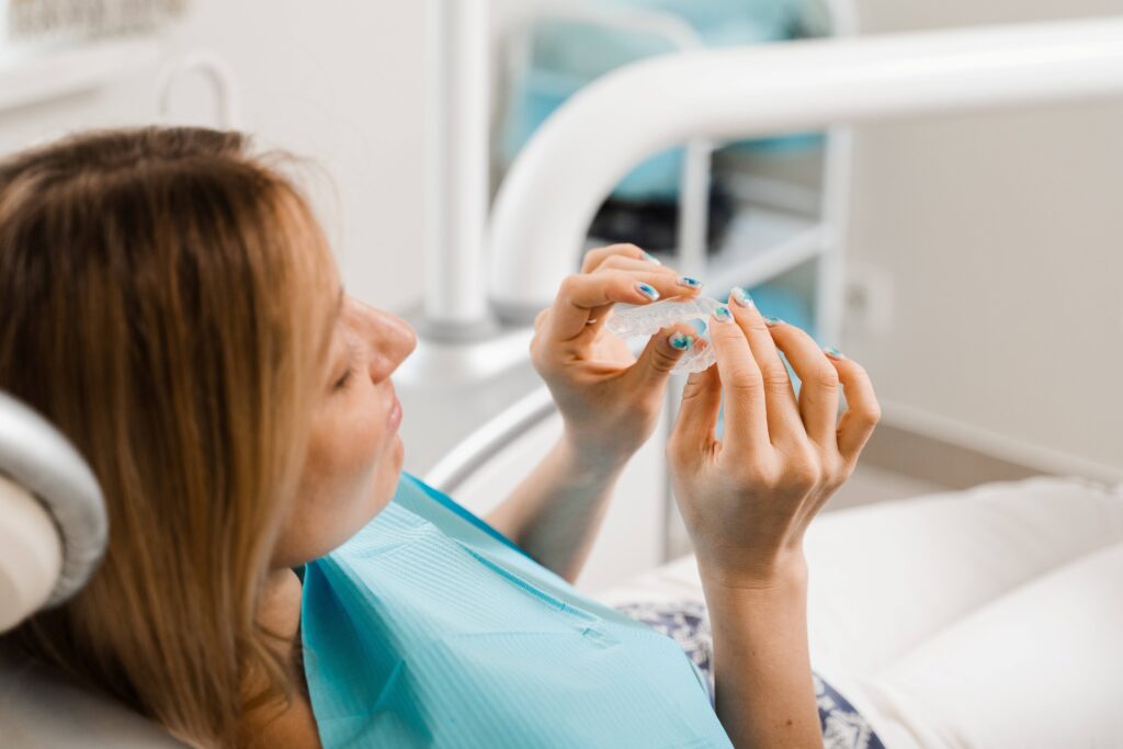 Smiling patient holding clear aligner in treatment room