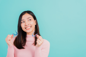 a patient smiling and holding their retainer